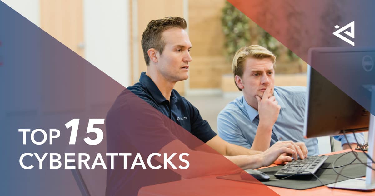 two men sitting at a computer desk, one an IT professional helping the other