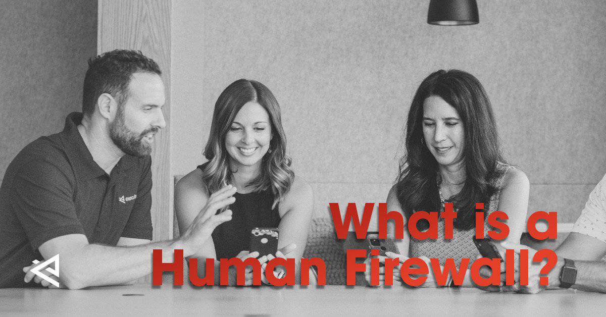 black and white photo of a man with short hair sitting at a table and helping 2 women with their work technology